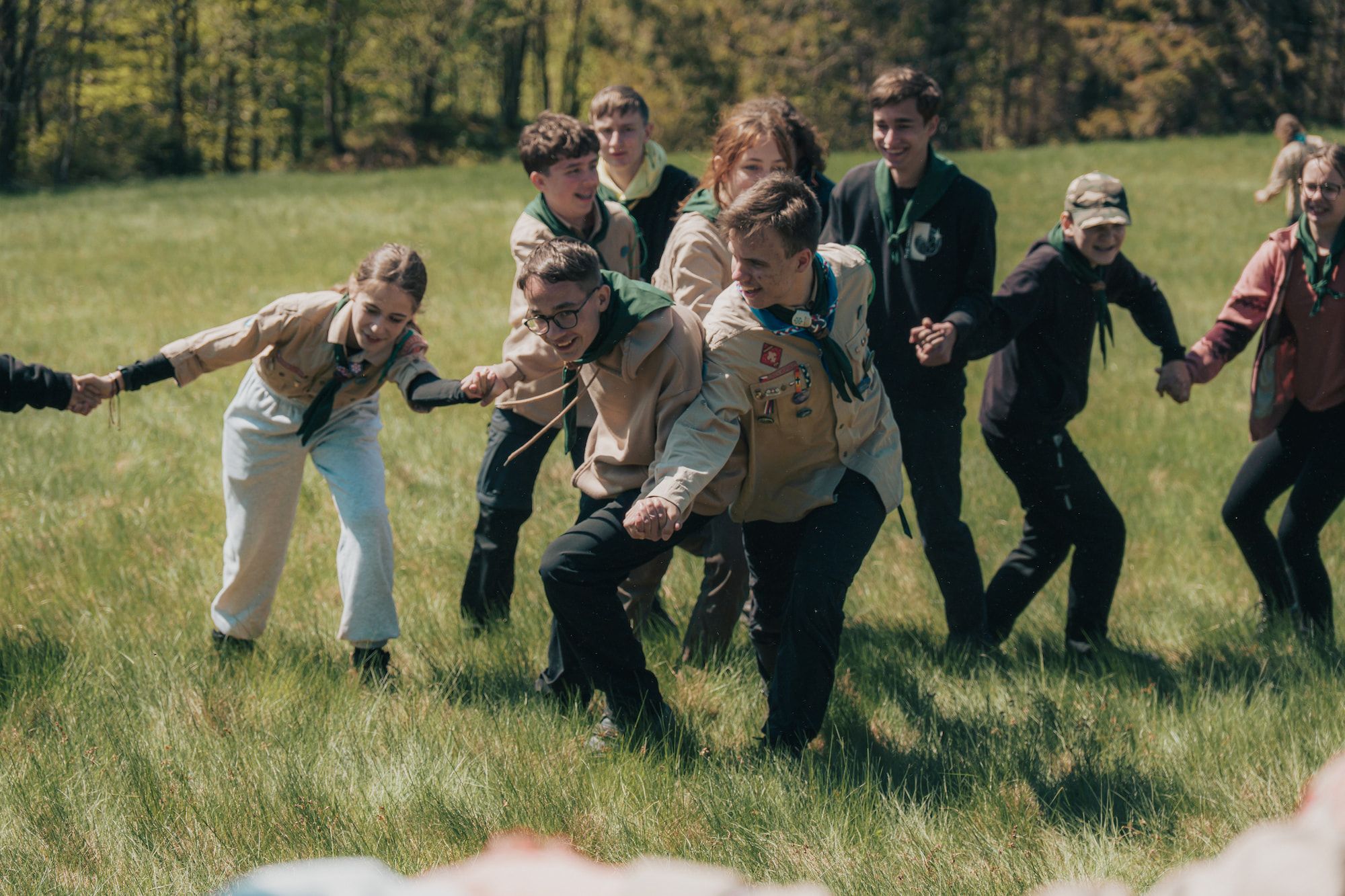 Skupina dětí hraje na louce, směje se a užívá si slunečného dne.